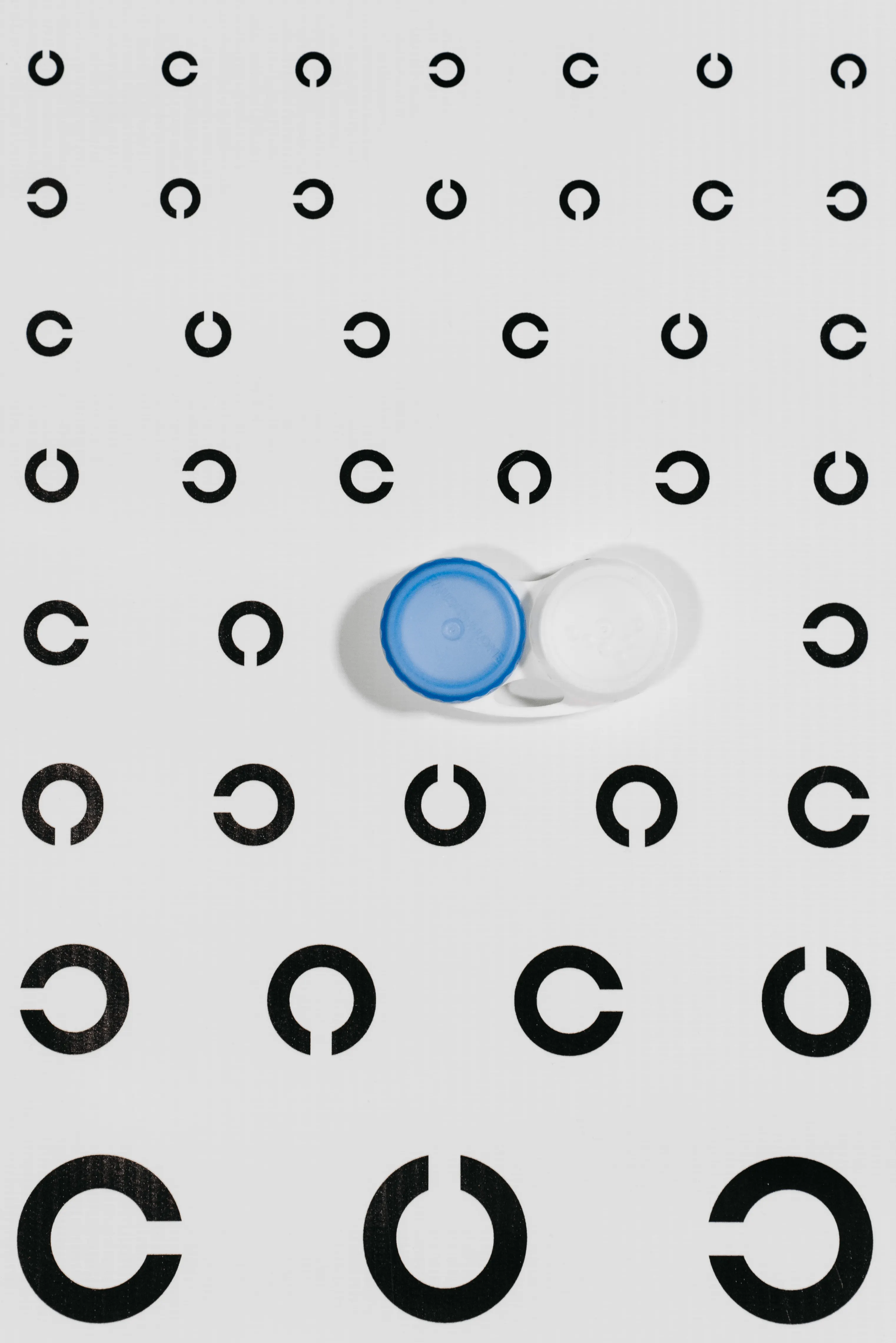 A contact lens case resting on an eye test chart